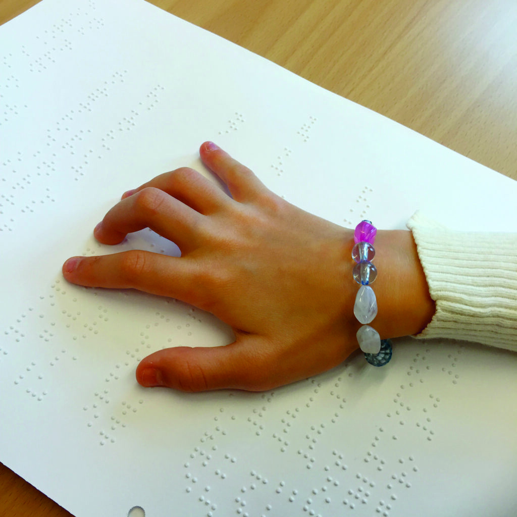 Bild på en hand över ett dokument med punktskrift.